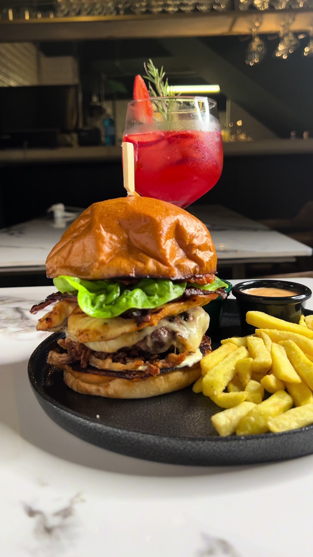 Hamburguesa alta de KRUDO con papas y un cóctel